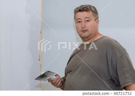 In room renovation worker plastered wall with plasterboard drywall to prepare for final stage In room renovation worker plastered wall with plasterboard drywall to prepare for final stage 98721752