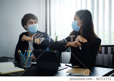 Business or accountant wear mask and bumping elbows for keeping social distance instead of hugs or handshake at morning in home office. Business or accountant wear mask and bumping elbows for keeping social distance instead of hugs or handshake at morning in home office. 98721753