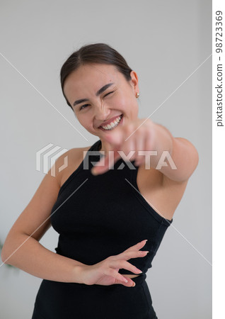 Smiling asian woman pointing her finger on white background. 98723369