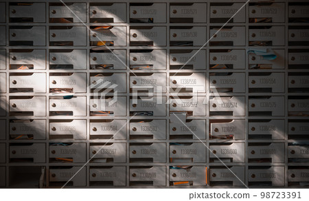 Beautiful sunlight shine on rows of white wooden mailboxes with keyholes for resident in condominium. Beautiful sunlight shine on rows of white wooden mailboxes with keyholes for resident in condominium. 98723391