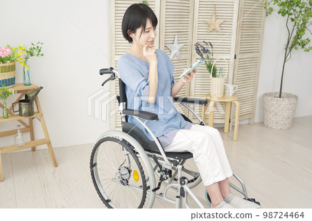 在家使用智能手機的輪椅的殘疾婦女 在家使用智能手機的輪椅的殘疾婦女 98724464