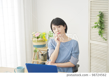 坐在輪椅上的殘疾婦女在家裡的電腦前思考 坐在輪椅上的殘疾婦女在家裡的電腦前思考 98724562