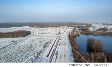 Winter frozen lake in a snowy forest top view. Frosty Christmas weather. 98725112