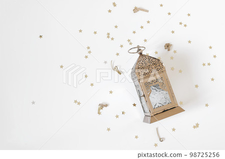 Festive Ramadan holiday composition, web banner. Golden ornamental Moroccan lantern and star shaped confetti isolated on white table background. Iftar party, Eid ul Fitr or Eid al Adha flatlay. Top. Festive Ramadan holiday composition, web banner. Golden ornamental Moroccan lantern and star shaped confetti isolated on white table background. Iftar party, Eid ul Fitr or Eid al Adha flatlay. Top. 98725256