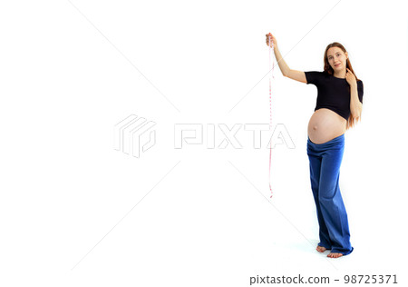 Pregnant woman measuring stomach with measuring tape 98725371