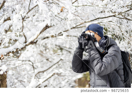 A middle-aged man who went on a photography trip with a camera on a snowy day A middle-aged man who went on a photography trip with a camera on a snowy day 98725635