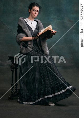 Book personage. Beautiful woman in image of Anna Karenina reading over vintage dark green background. Vintage style. Concept of literature character, history Book personage. Beautiful woman in image of Anna Karenina reading over vintage dark green background. Vintage style. Concept of literature character, history 98725937