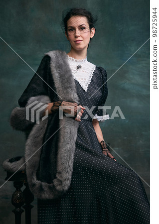Proud woman. Beautiful woman in image of Anna Karenina posing in retro dress over vintage dark green background. Concept of literature character, history Proud woman. Beautiful woman in image of Anna Karenina posing in retro dress over vintage dark green background. Concept of literature character, history 98725944