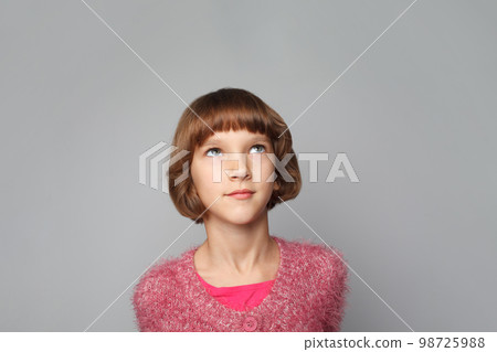 Pretty child girl looking up on grey background Pretty child girl looking up on grey background 98725988