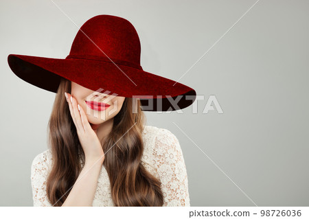 Young woman in wide broad brim hat. Pretty model with red lips makeup and cute smile portrait Young woman in wide broad brim hat. Pretty model with red lips makeup and cute smile portrait 98726036