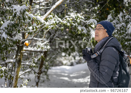 A middle-aged man who went on a photography trip with a camera on a snowy day A middle-aged man who went on a photography trip with a camera on a snowy day 98726187