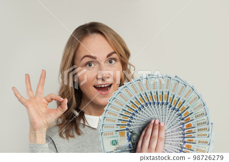 Happy woman holding fan of us dollars money showing ok sign on white background. Happy woman holding fan of us dollars money showing ok sign on white background. 98726279