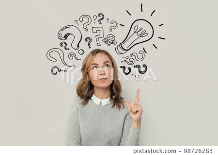 Cute woman in gray sweater have an idea and pointing up on light bulb against grey background Cute woman in gray sweater have an idea and pointing up on light bulb against grey background 98726283