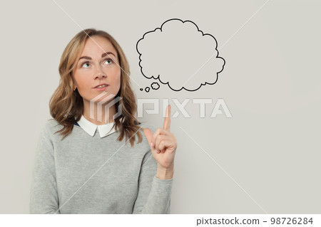 Cute woman in gray sweater pointing to think cloud on grey background 98726284