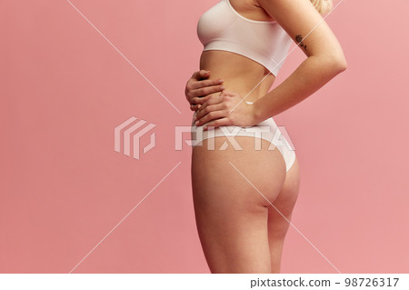 Back view of cropped female body in white inner wear isolated over pink background. Anti-cellulite care cosmetology. Concept of beauty, body care, health, plastic surgery 98726317