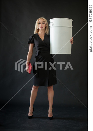 Beautiful blonde woman wth red clutch and white barrel on black background 98726632