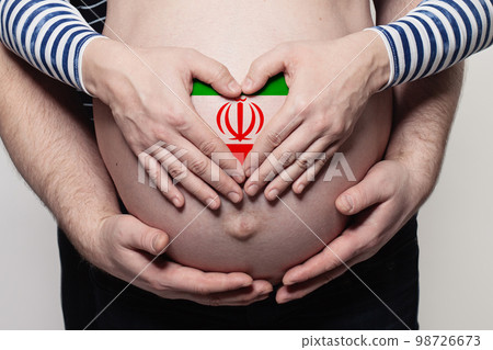 Iranian family concept. Man embracing pregnant woman belly and heart with flag of Iran 98726673