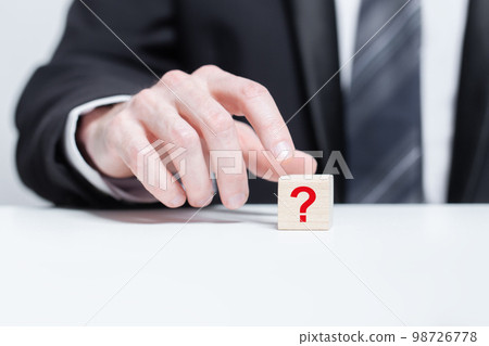 Red question mark on wooden block pyramid in businessman hand. FAQ question concept Red question mark on wooden block pyramid in businessman hand. FAQ question concept 98726778
