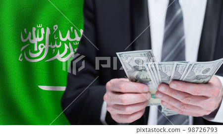 Hands holding dollar money on flag of Saudi Arabia 98726793