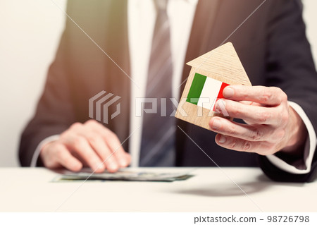 Businessman hand holding wooden home model with Italian flag. insurance and property concepts 98726798