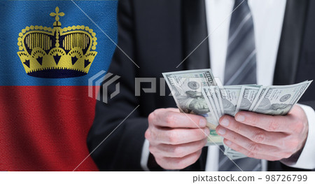 Hands holding dollar money on flag of Liechtenstein 98726799