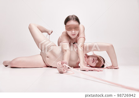 Abstract art. Portrait of two young girls posing in underwear and ropes with eyes closed over light studio background. Concept of weird people, contemporary photography 98726942