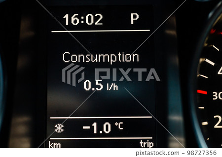 Screen on dashboard of car shows fuel consumption at idle and air temperature outside 98727356