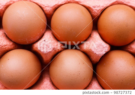 Open egg box with ten brown eggs close up view. Fresh organic chicken eggs in carton pack or egg container 98727372
