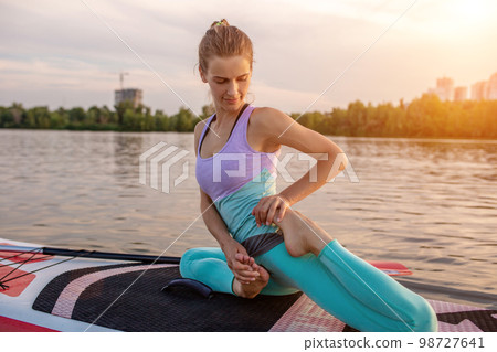 Young beautiful woman meditating in a sea at SUP paddleboarding. Healthy lifestyle. 98727641