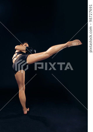 Athletic woman in boxing gloves is practicing karate in studio. Athletic woman in boxing gloves is practicing karate in studio. 98727691