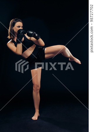 Athletic woman in boxing gloves is practicing karate in studio. 98727702