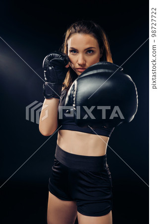 Athletic woman in boxing gloves is practicing karate in studio. 98727722