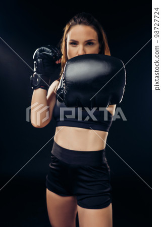 Athletic woman in boxing gloves is practicing karate in studio. 98727724