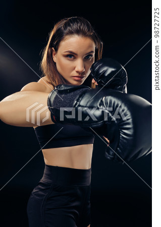 Athletic woman in boxing gloves is practicing karate in studio. 98727725