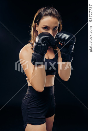 Athletic woman in boxing gloves is practicing karate in studio. 98727727