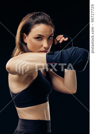 Athletic woman in boxing mittens is practicing karate in studio. Athletic woman in boxing mittens is practicing karate in studio. 98727729