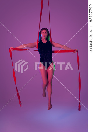 Beautiful girl in a black swimsuit is performing an acrobatic elements in studio. Beautiful girl in a black swimsuit is performing an acrobatic elements in studio. 98727740