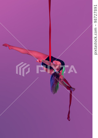 Beautiful girl in a black swimsuit is performing an acrobatic elements in studio. 98727891