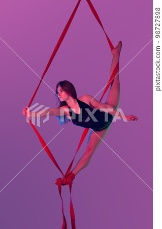 Beautiful girl in a black swimsuit is performing an acrobatic elements in studio. 98727898