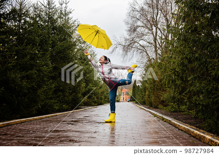 Coping with stress and anxiety. Practicing mindfulness and relaxation techniques. Happy senior woman in yellow rain coat with yellow umbrella walking and enjoying life in rainy park Coping with stress and anxiety. Practicing mindfulness and relaxation techniques. Happy senior woman in yellow rain coat with yellow umbrella walking and enjoying life in rainy park 98727984