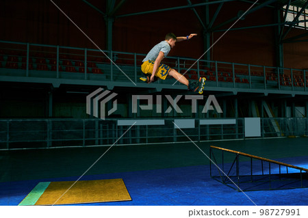 The man performs a trick. Jump. Indoor training The man performs a trick. Jump. Indoor training 98727991