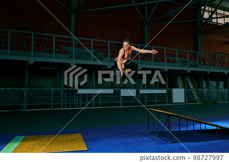 The young woman performs a trick. Jump. Indoor training 98727997