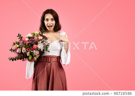 Glad young caucasian lady in casual with open mouth, show finger at herself, hold bouquet of flowers Glad young caucasian lady in casual with open mouth, show finger at herself, hold bouquet of flowers 98728586