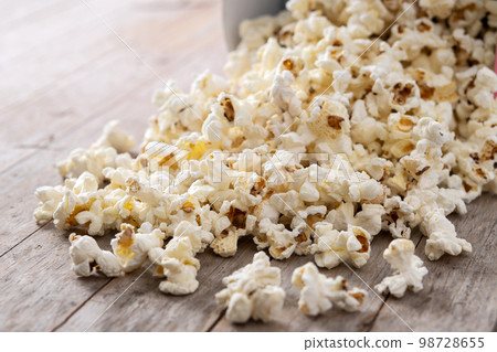 Salted popcorn scattered on wooden table Salted popcorn scattered on wooden table 98728655