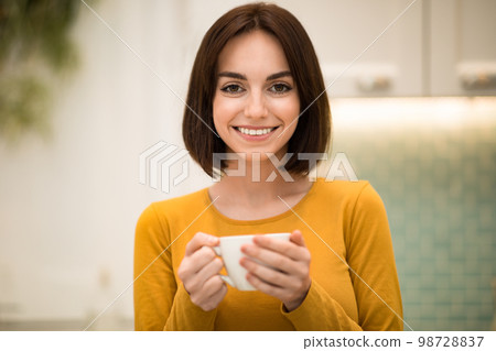 Portrait of young woman enjoying fresh aromatic coffee in kitchen 98728837