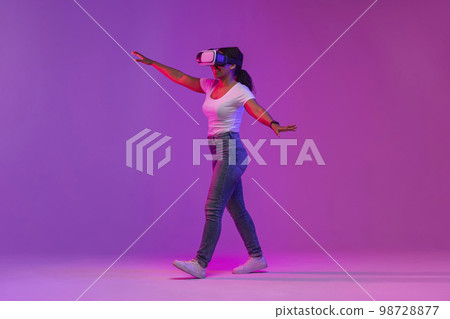 Excited Black Lady Wearing VR Headset Experiencing Virtual Reality In Neon Light 98728877