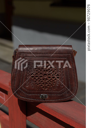 small brown women's leather bag with a carved pattern. selective focus small brown women's leather bag with a carved pattern. selective focus 98729076