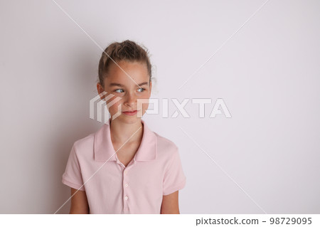 Little emotional teen girl in pink shirt 11, 12 years old on an isolated white background. Children's studio portrait. Place text, to copy space for inscription, advertising children's goods. Little emotional teen girl in pink shirt 11, 12 years old on an isolated white background. Children's studio portrait. Place text, to copy space for inscription, advertising children's goods. 98729095