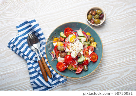 Greek salad with feta cheese, vegetables, olives in blue bowl on white wooden background 98730081