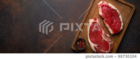 Two raw meat beef rib eye marbled steaks on wooden cutting board Two raw meat beef rib eye marbled steaks on wooden cutting board 98730104